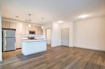an empty living room with a kitchen with stainless steel appliances at Century Town Center, Gainesville, Florida